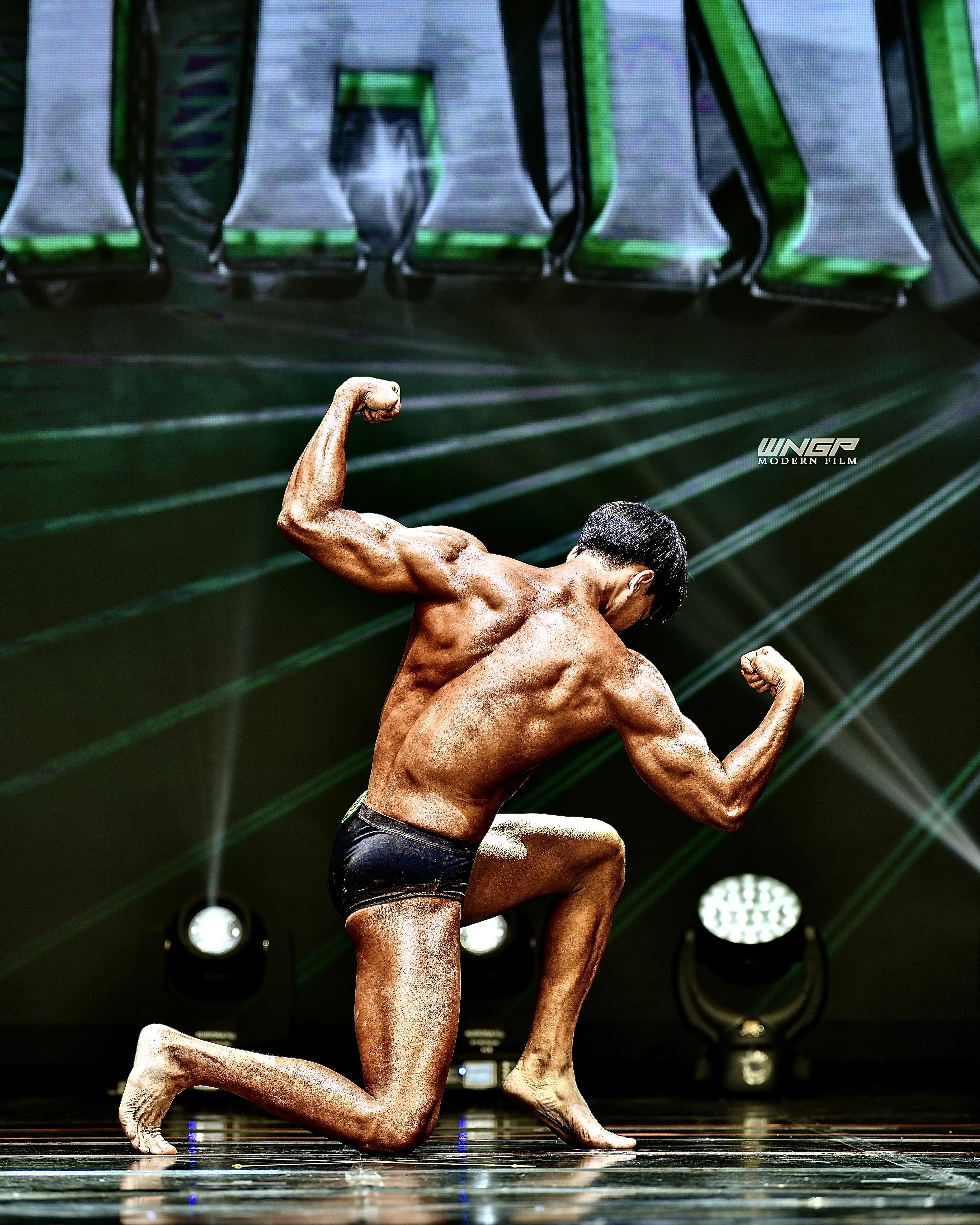 Coach Kang Jaehyun posing at a natural bodybuilding competition — the athletic background behind BODY SMITH boxing coaching