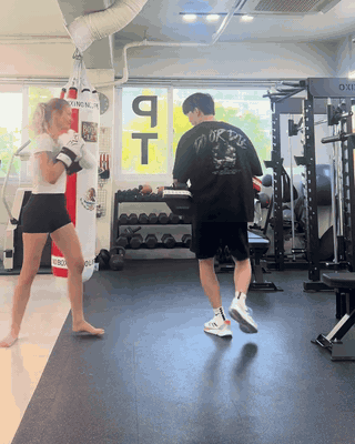 A member practicing punches and kicks with a coach during private mitt training at BODY SMITH